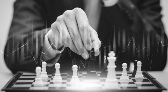 A line graph is overlaid atop a black and white image of a man in a suit playing chess as the pieces softly glow