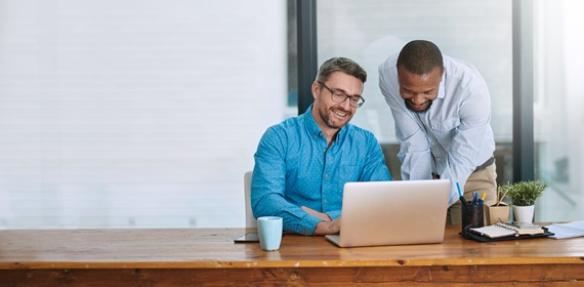 Two businessmen working on a laptop in a clean, modern office
