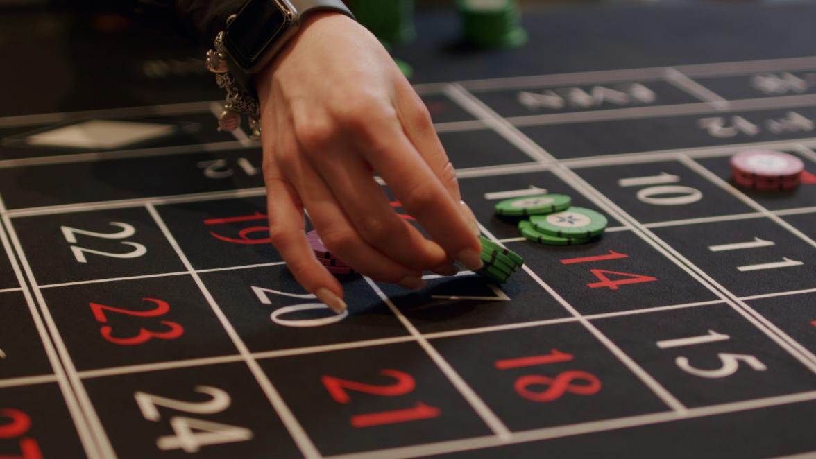 Close-up of hand of roulette player placing bets at an elite casino. Gambling, nightlife