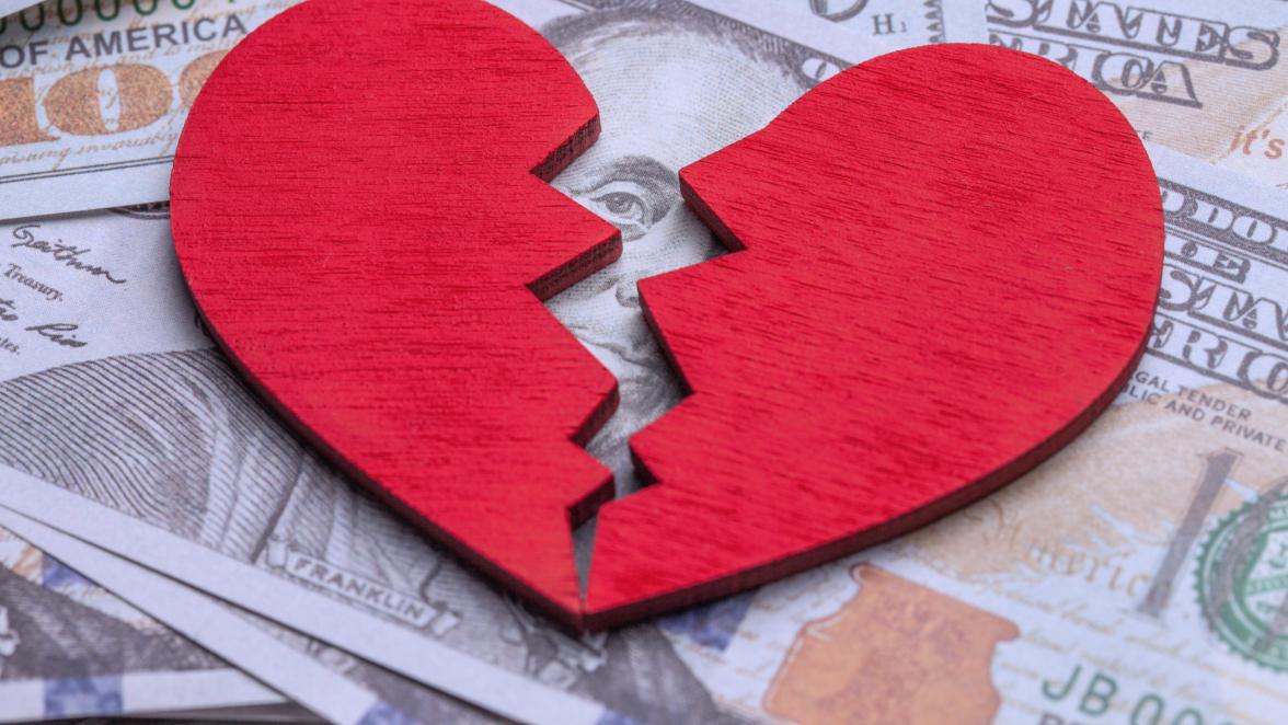 Broken heart because of money. Heart on a stack of cash dollars. Crack in the red heart, Breaking the relationship.