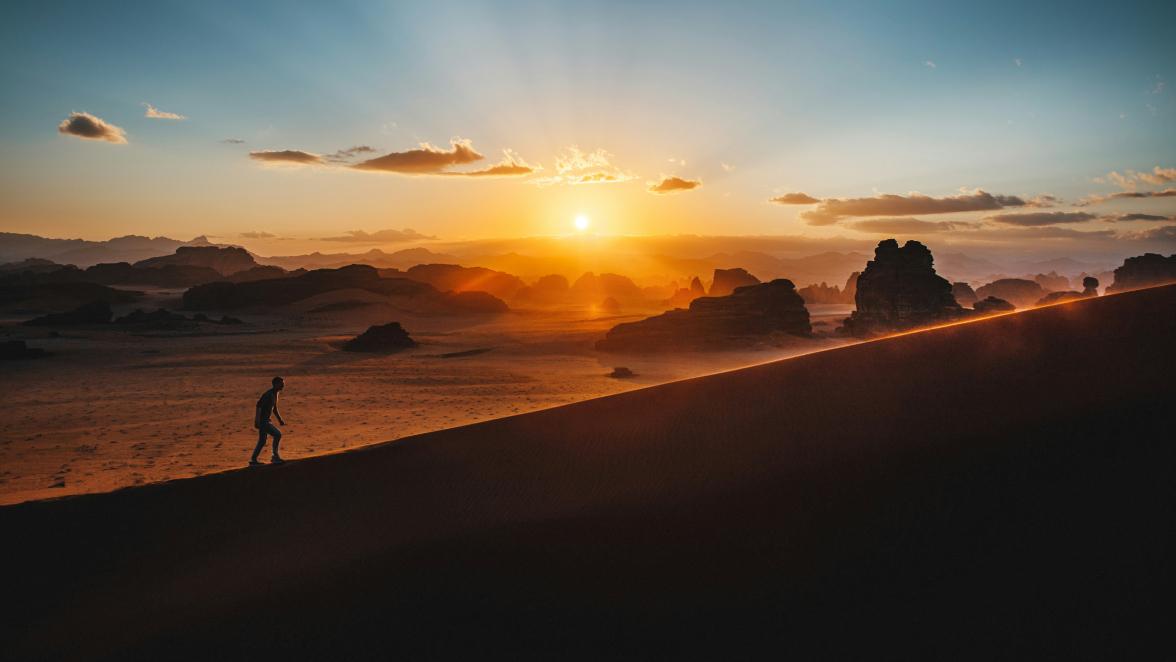 hiker walking up a hill at sunrise