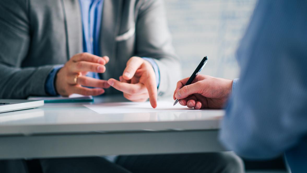 A business consultant and a client meeting in an office, signing a contract.