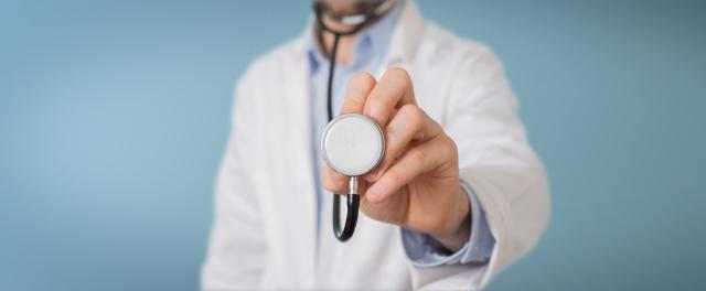 Doctor on blurred background using stethoscope in hospital