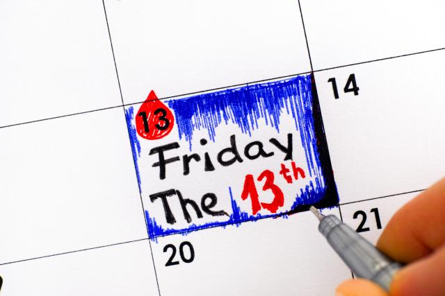 woman-fingers-with-pen-writing-reminder-friday-the-13th-in-calendar