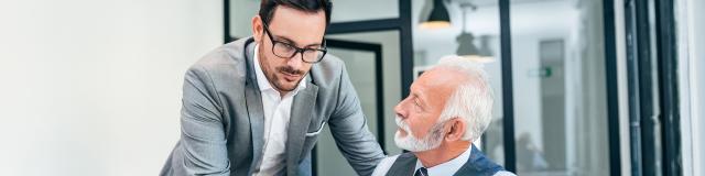 Young man discussing with boss or older employee in modern office.