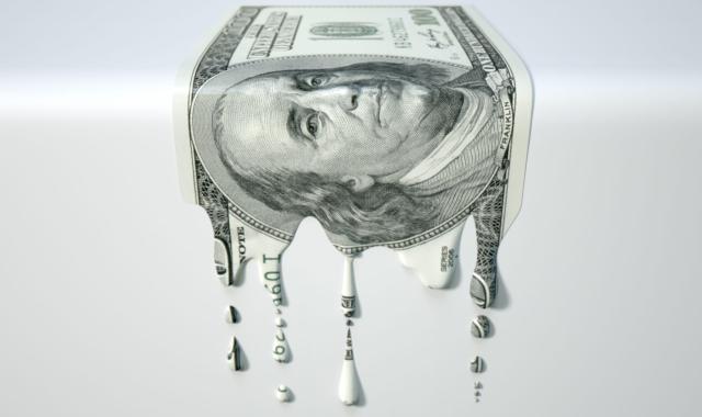 A concept image showing a regular US Dollar banknote that is half melted and liquified dripping on an isolated studdio background