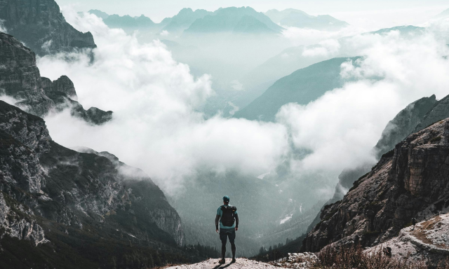 Hiker Overlooking Mountain Peaks With Clouds