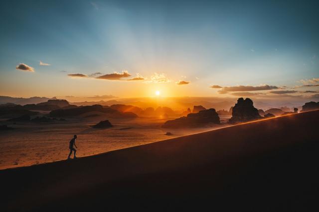 hiker walking up a hill at sunrise