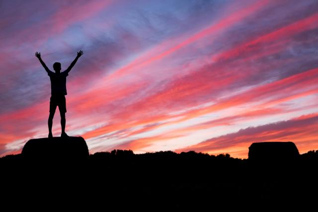 Hiker with raised arms watching a sunset