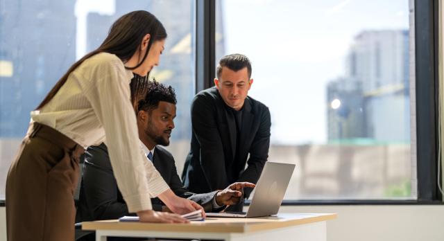 group of professionals looking at a laptop