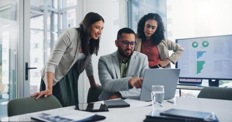 A group of professionals in a meeting room review reports. 