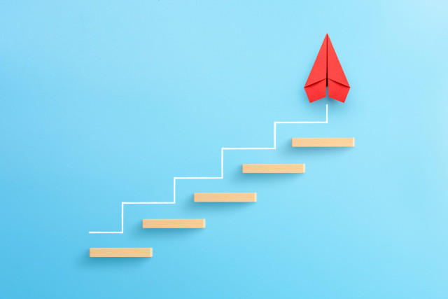 wooden-block-stacking-as-step-stair-with-red-paper-plane-on-blue-background-ladder-of-success-in-business-growth-concept-copy-space