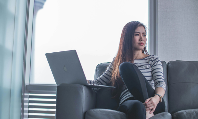 Woman on couch looking away from laptop