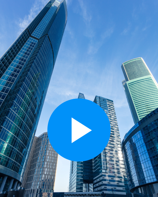 Modern skyscrapers against a clear blue sky, with a large blue play button icon in the center, indicating a video.