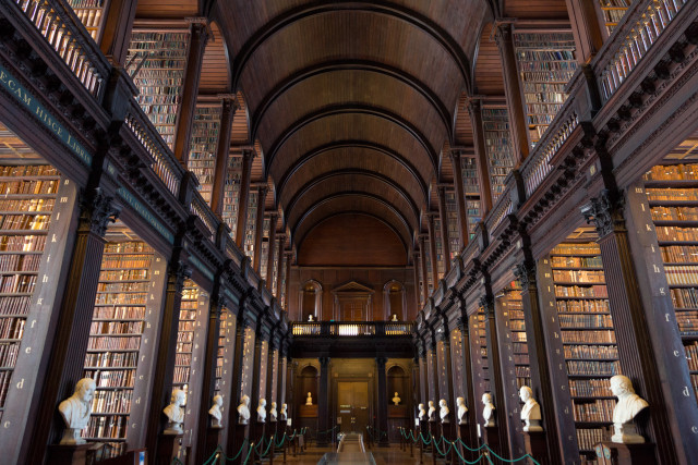 Historical library hall with shelves of vintage books and Greek busts