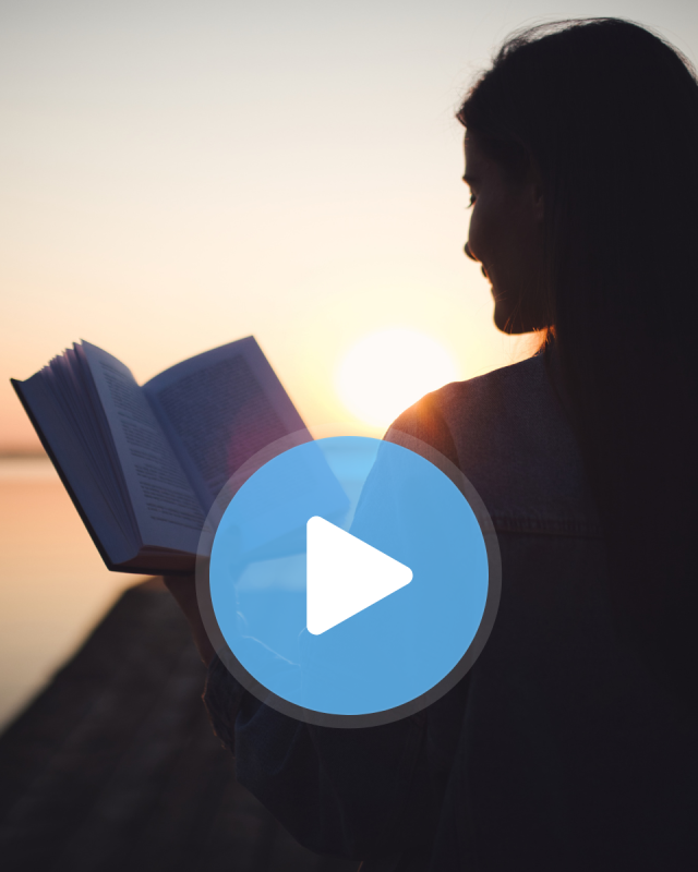 A silhouette of a woman reading a book at sunset