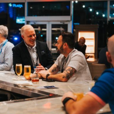 Two gentleman seated at barstools smile and talk Elaborate buffet setup at an upscale bar