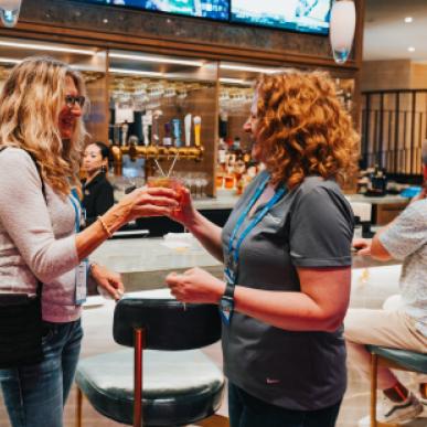 Two woman cheers each other at a bar