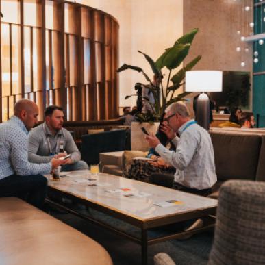 Small group of gentleman sit around a coffee table at an upscale bar